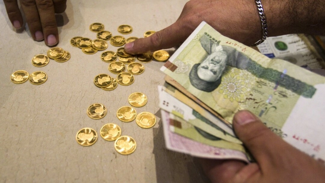A customer buys Iranian gold coins at a currency exchange in Tehran